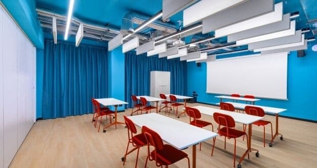 Aula formativa CX con banchi modulari e schermo di proiezione